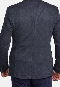 Mörkblå kavaj med en texturerad, rutmönstrad yta. Har en skräddarsydd passform och en singel bakventil. Knappar på ärmarna ger extra detalj.