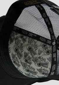 Black baseball cap featuring a mesh back, with a patterned interior displaying black-and-white graphics of eyes and wings. Accented with branding.