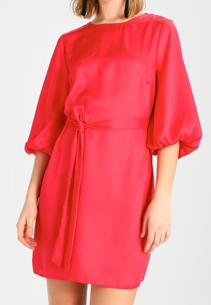 Svetle růžové krátké šaty vyrobené z hladké tkaniny, s nabíranými rukávy a uvázaným pasem. Jednoduchý design s kulatým výstřihem a jemným leskem.