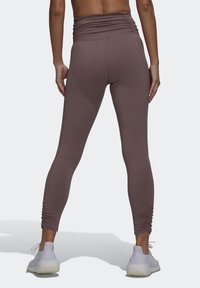 Højtaljede, tætsiddende leggings i en afdæmpet mauve farve, fremstillet af strækbart stof. Har en samlede tekstur langs taljen og smalle ben.