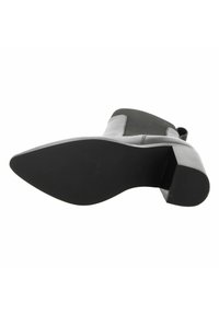 Suela negra y tacón cuadrado de bota de tobillo de cuero gris con panel lateral elástico y tirador, vista desde abajo sobre fondo blanco.