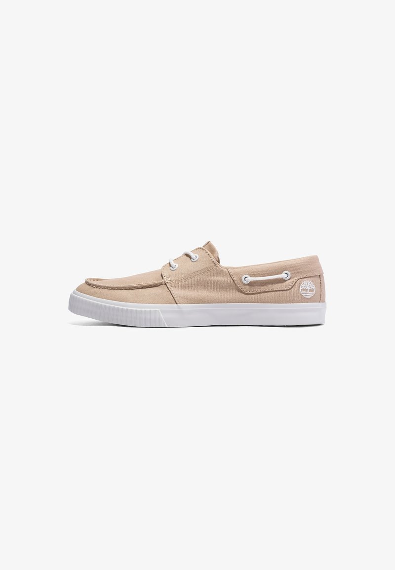 Chaussure bateau en toile beige avec semelle en caoutchouc blanche, lacets blancs et détails cousus, avec un petit logo arbre blanc près du talon.