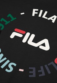 Tela negra con texto impreso, con la palabra "FILA" en blanco y rojo, rodeada de acentos de colores y elementos de diseño en forma circular.