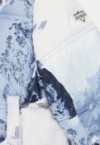 Gewatteerde jas in een blauw-wit abstract bergmotief. Beschikt over een zwart Guess-logo op de bovenste rechtermouw. Gladde, glanzende stof.