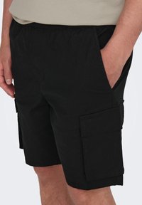 Pantaloni cargo neri realizzati in tessuto leggero, con cintura elastica, tasche laterali e due grandi tasche cargo.