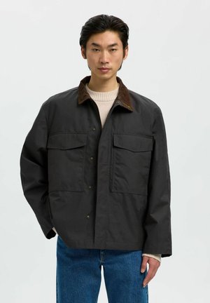 Black jacket with a corduroy collar, two front pockets, button-up closure, and a relaxed fit. Worn over a light sweater and blue jeans.