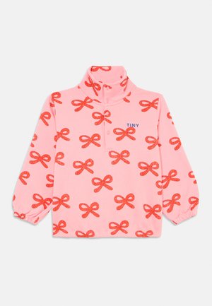 Roza dolgi rokav pulover za dojenčke z rdečimi vzorci pentelj, gumbnim visokim ovratnikom, elastičnimi manšetami in napisom "TINY" na levem prsnem delu.