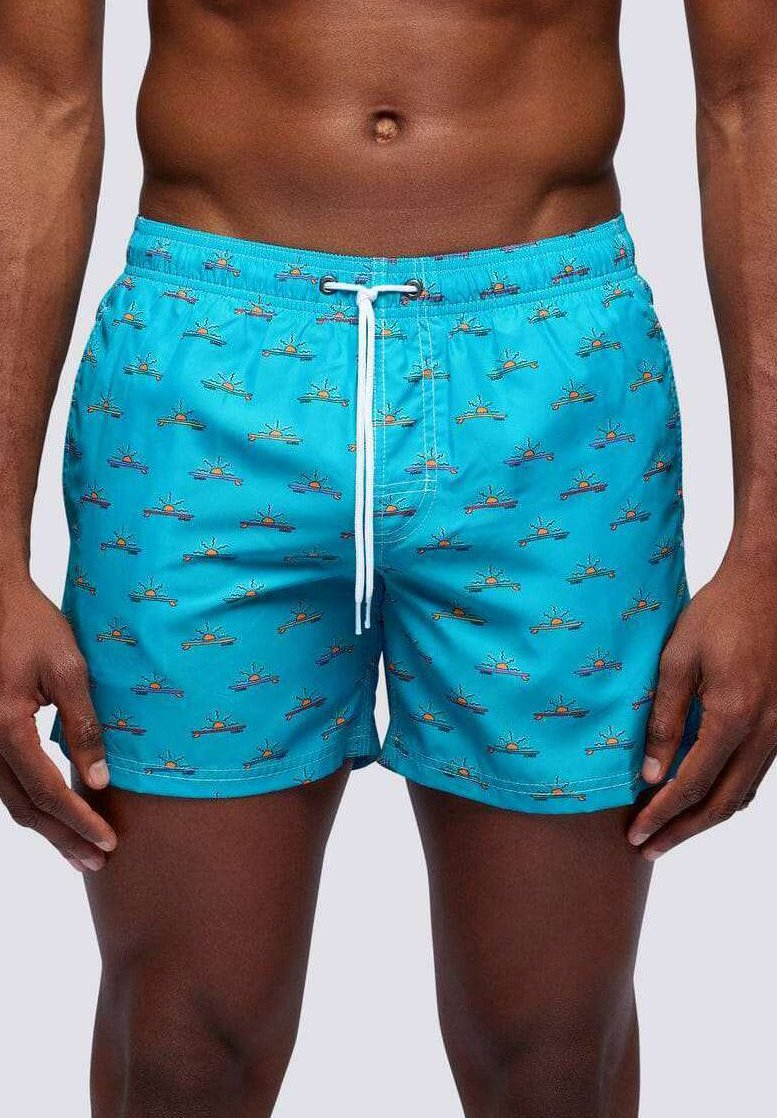 Pantaloni da bagno turchesi con un motivo di barche colorate e soli. Il materiale è liscio, con una vita regolabile tramite cordino.
