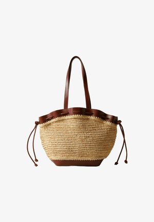 Sac fourre-tout en paille tissée avec garniture en cuir marron, longues anses et cordons de serrage des deux côtés.