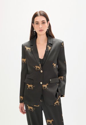 Blazer de satén negro con estampado de leopardo dorado, solapas con muesca, bolsillos frontales y cierre de botones dorados. Combinado con un conjunto a juego con el mismo patrón.
