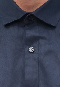 Marineblauw poloshirt met een klassieke kraag en een knoopsluiting bij de hals. Het materiaal oogt glad met een lichte glans.