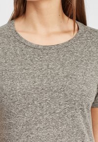 Šedé tričko s krátkým rukávem vyrobené z měkkého bavlněného směsového materiálu, s klasickým kulatým výstřihem a mírně strukturovaným povrchem.