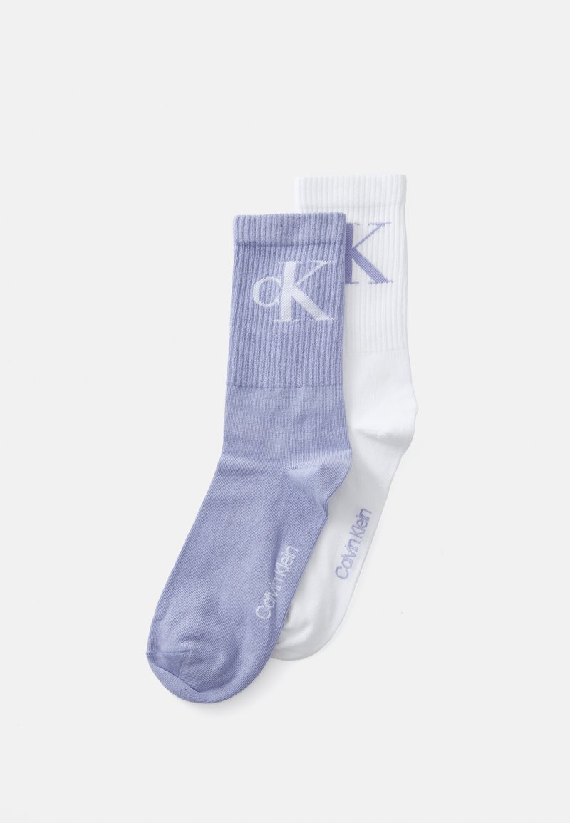 Dos pares de calcetines de tripulación: uno en púrpura claro con un puño acanalado y un logotipo blanco, el otro en blanco sólido con un logotipo púrpura.