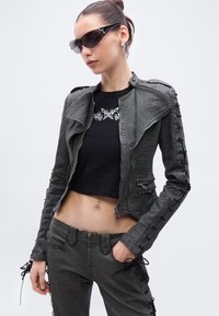 Hall hall denimjakk asümmeetrilise krae, tõmblukkudega taskute ja pitsist detailidega varrukatel. Kandmiseks koos musta lühikese topi ja sobivate hallide pükstega.