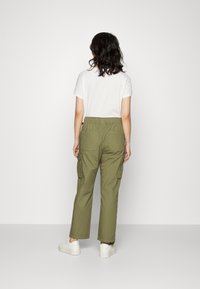 Olijfgroene cargobroek met een relaxte fit, elastische tailleband, twee grote achterzakken en zijzakken; gedragen met een eenvoudige witte T-shirt.