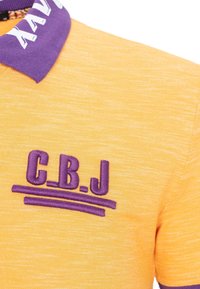 Geel poloshirt met een gestructureerde afwerking, voorzien van een paarse kraag en geborduurd "C.B.J." ontwerp op de borst.