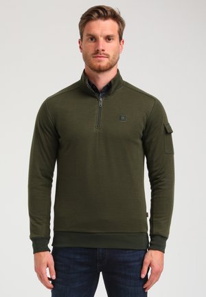 Sudadera de medio cierre color verde oliva, hecha de una tela suave, con puños y dobladillo acanalados, que presenta un pequeño logo y un bolsillo de utilidad en la manga.