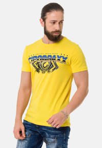 Yellow short-sleeve t-shirt with graphic print featuring text and geometric designs. Made from cotton, smooth texture, crew neckline.