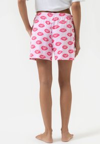 Roze shorts van katoen, met een herhaald lippenmotief in donkerder roze. Elastische tailleband met een eenvoudige achterkant. Soepele textuur.
