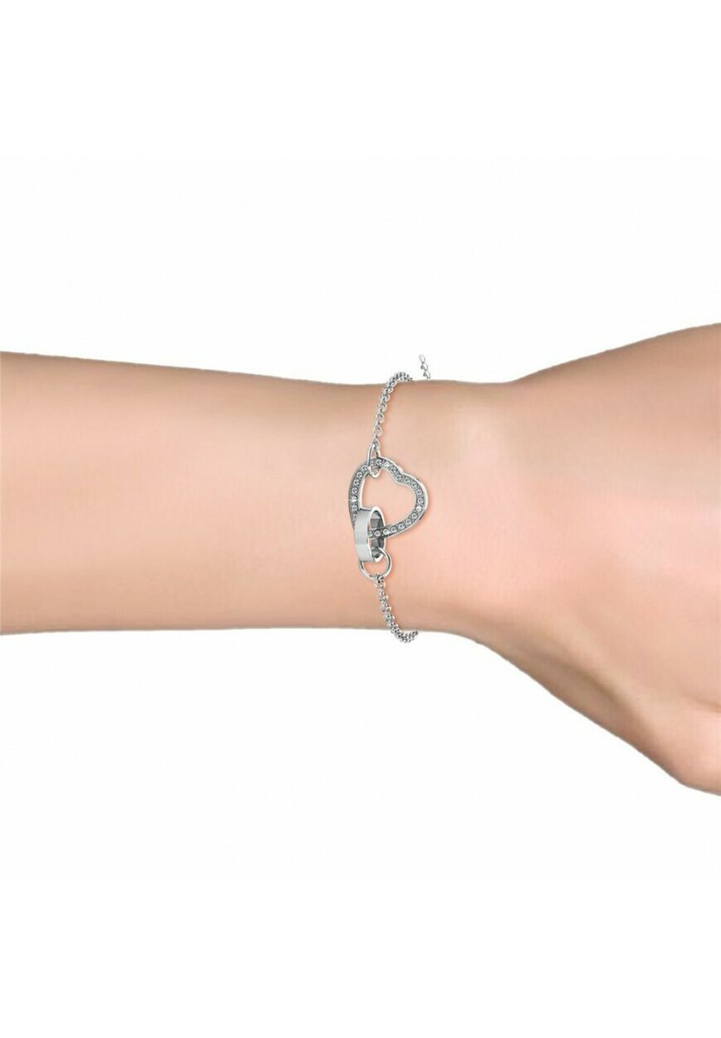 Silberarmband mit einem herzförmigen Design. Das Herz hat einen zentralen Verschluss und ist entlang der Kanten mit kleinen klaren Steinen verziert.
