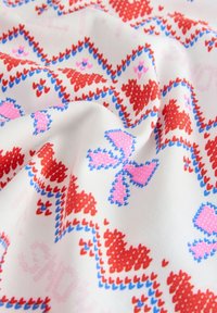 Cotton fabric featuring a repeating pattern of red and pink hearts, accented with blue details on a white background, with a soft texture.