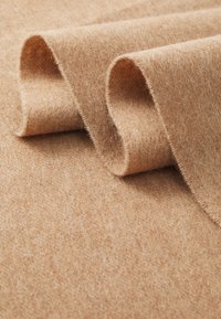 Kollane villakangas pehmea ja tekstuurne pind, koos volditud äärtega, mis näitavad looduslikku viimistlust ning õrnu värvitoone.