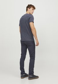 Camisa de rayas navy de manga corta combinada con pantalones oscuros y zapatillas negras. La camisa tiene un corte clásico y una textura sutil.