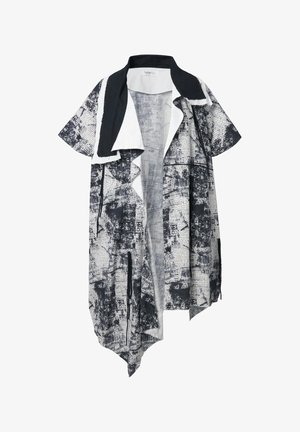 Sorte og hvide mønstrede open-front jakke med korte ærmer, asymmetrisk kant og kontrasterende kravedetaljer. Lavet af letvægtsstof.