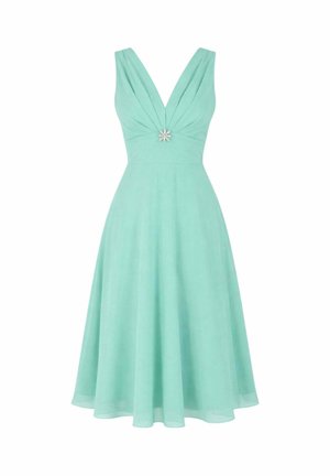 Vestito senza maniche verde menta fino al ginocchio con scollatura a V profonda e una spilla decorativa al centro davanti.