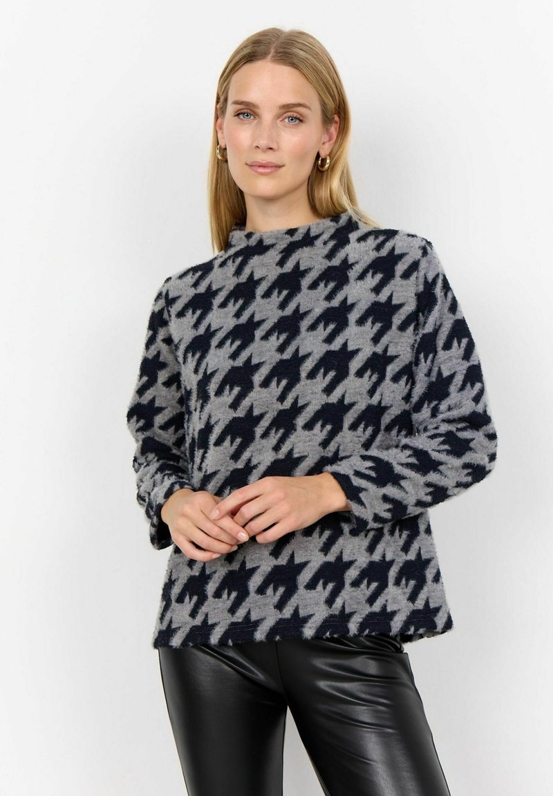 Kudum, millel on tume tume meresinine ja hall houndstooth muster, valmistatud pehmest kangast, kõrge kaelusega ja pikkade varrukatega.
