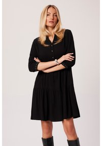 Czarna sukienka koszulowa z warstwowym dołem, zapinana na guziki z przodu, z rękawami o długości 3/4 z guzikami oraz gładką teksturą materiału.