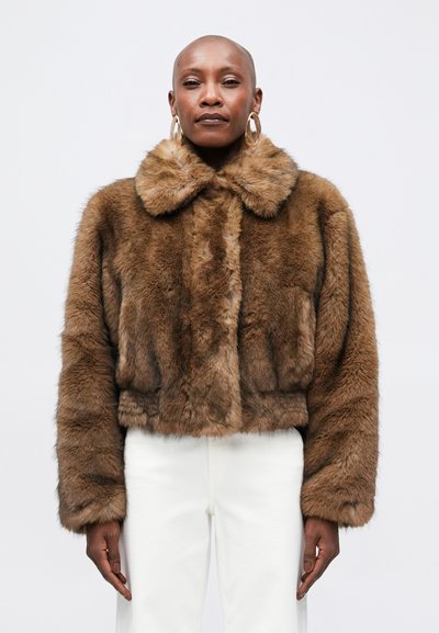 Brown faux fur cropped jacket with a wide collar and long sleeves, featuring a soft texture and subtle sheen. Worn over white pants.