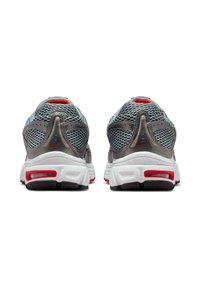 Zapatillas deportivas grises con parte superior de malla, suela intermedia blanca con detalles rojos y suela exterior de goma negra. Diseño redondeado con secciones ventiladas.