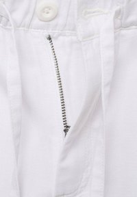 Pantaloni bianchi in cotone con zip, chiusura con bottone superiore e cordoncino. La texture è liscia con dettagli di cucitura ben visibili.