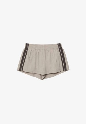 Pantaloncini beige con vita elasticizzata e strisce verticali scure sui lati, realizzati in tessuto leggero, distesi su uno sfondo bianco.