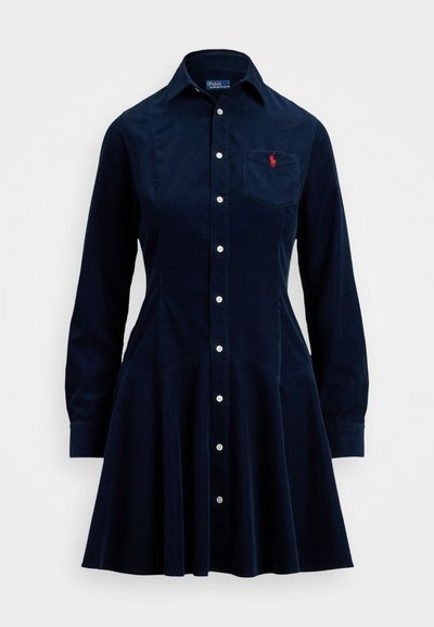 Granatowa sukienka koszulowa z cordurowej tkaniny z guzikami z przodu, długimi rękawami, kołnierzykiem, kieszenią na piersi oraz rozkloszowanym dołem.