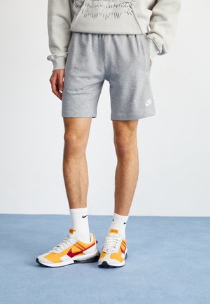 Gray cotton shorts with an elastic waistband and side pockets; worn with white and orange Nike sneakers and white socks featuring the Nike logo.