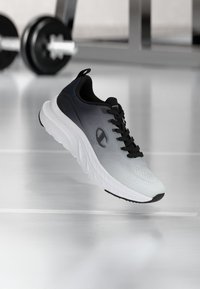 Αθλητικό παπούτσι σε ασπρόμαυρο με λείο πλέγμα στο στρώμα επάνω, στρογγυλεμένη μύτη, πάτο με παχύ μαξιλαράκι και υφή από καουτσούκ στην εξωτερική σόλα.