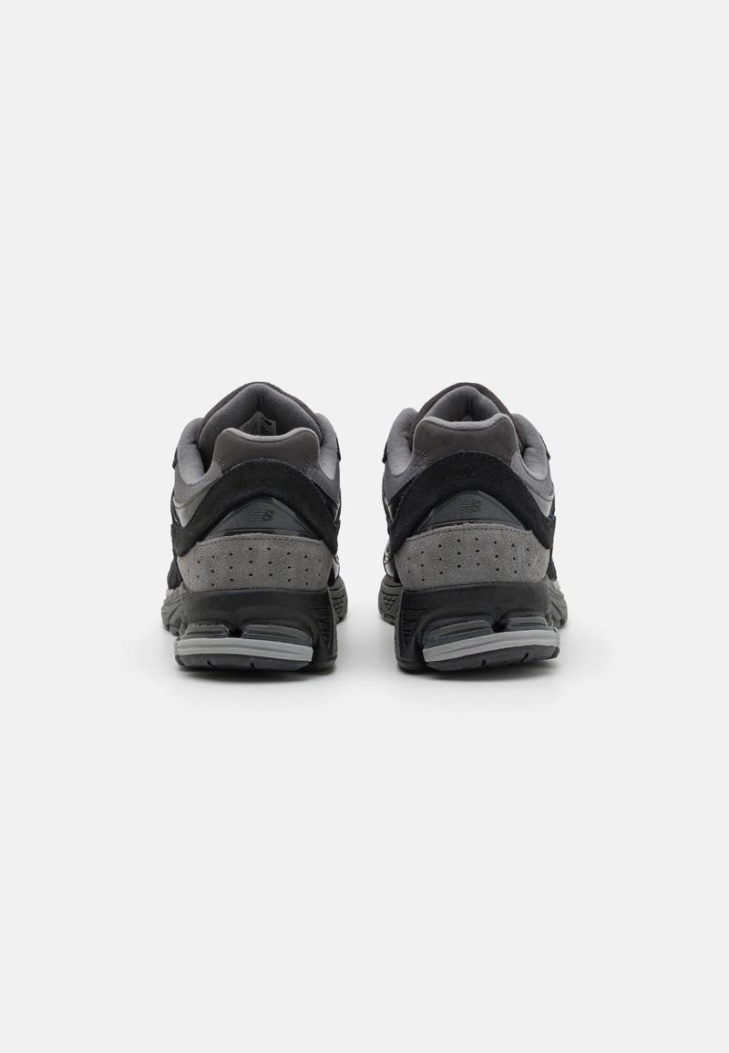 Sportschoenen in zwart en grijs tinten, gemaakt van suede en mesh materialen, met gewatteerde kraag en getextureerde zolen voor grip.