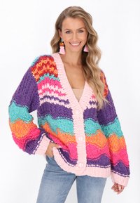 Flerfärgad stickad cardigan med böljande mönster i rosa, orange, lila och teal, med knappar i rosa framtill och ribbade ärmslut.