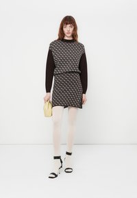 Abito a righe in bianco e nero con parte superiore in maglia, vita aderente e gonne svasata. Abbinato a collant nudi e sandali neri con tacco.