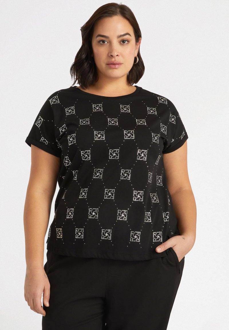 Top negro de manga corta con un patrón geométrico y acentos plateados. Fabricado en tejido suave con un ligero brillo y un diseño de corte relajado.