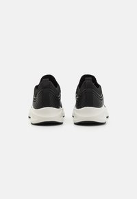 Black athletic shoes with a textured mesh upper, contrasting white midsole, and subtle curved accents along the sides.