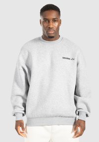 Sweatshirt gris à manches longues, avec un col ras du cou en côtes et des poignets côtelés, arborant un logo brodé noir "SMILODOX Ltd." sur la poitrine.