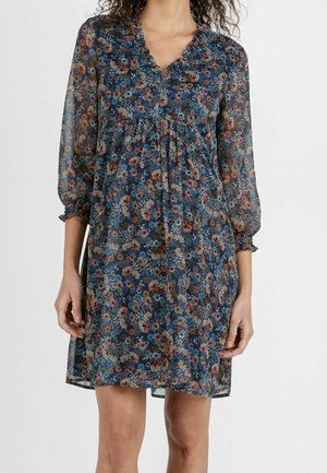Sukienka w kwiatowy wzór z przezroczystej granatowej tkaniny. Posiada dekolt w serek, trzy czwarte rękawów z bufkami oraz marszczenie pod biustem.