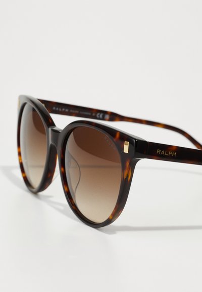 Braune Schildpatt-Sonnenbrille mit übergroßen, runden Rahmen. Verlaufsgläser und goldene Akzente an den Bügeln. Mit "RALPH"-Markierung.