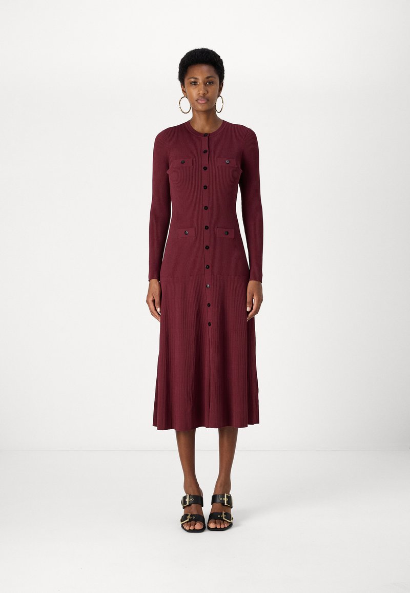 Burgundy bordázott midi ruha hosszú ujjal, gombos elülső résszel és két mellzsebbel. Fekete gombokkal díszített, fekete platform szandálokkal viselve.