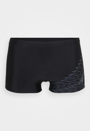 Schwarze Badeshorts aus glattem Material, mit einem eleganten Design und einem Zickzackmuster in Hellgrau an der unteren Seite.