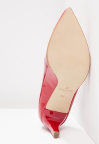 Chaussure à talon haut pointu en cuir verni rouge, vue de la semelle avec la taille 4½ et la marque "Peter Kaiser".