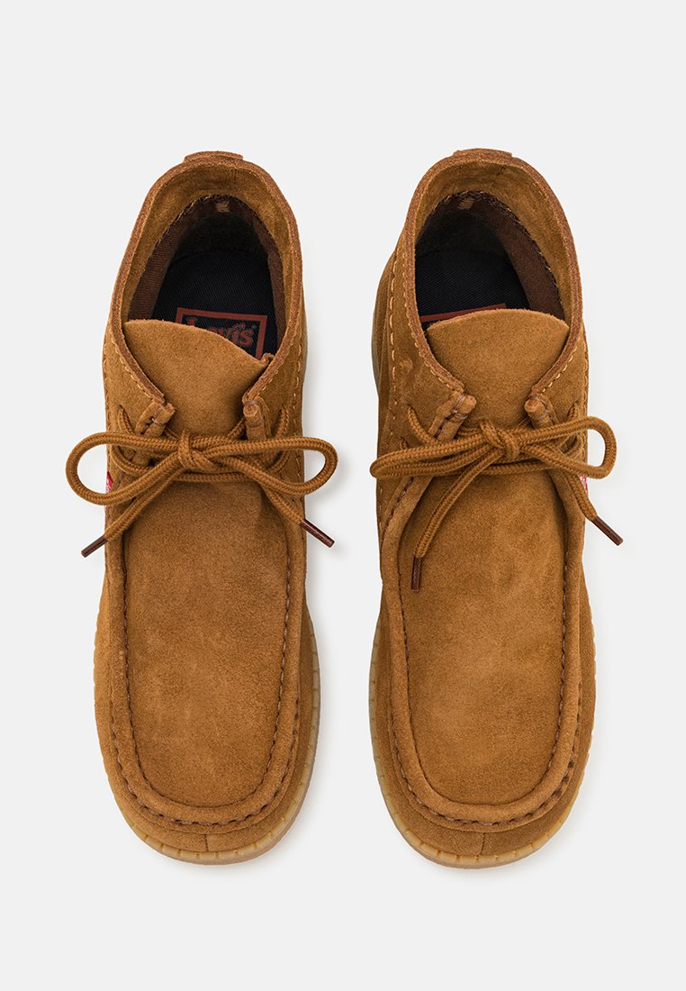 Chaussures en suede marron avec un design à cheville basse, dotées de lacets, d'un bout rond, d'une surface texturée et d'un intérieur rembourré.